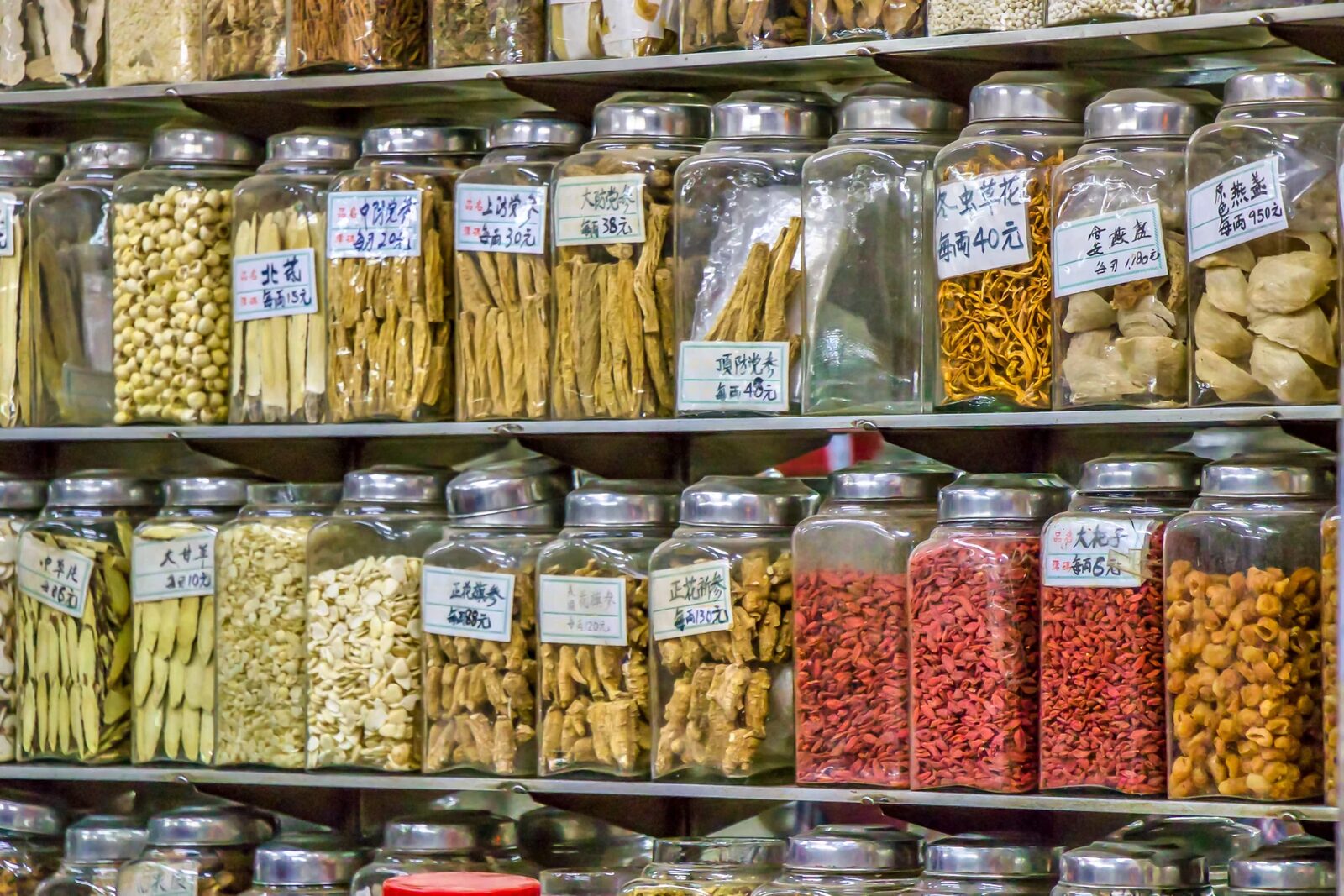 Shelves of labelled jars holding dried botanical raw materials in an Asian supply market