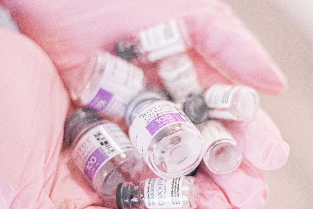 Gloved hands handling small laboratory vials used in pharmaceutical formulation
