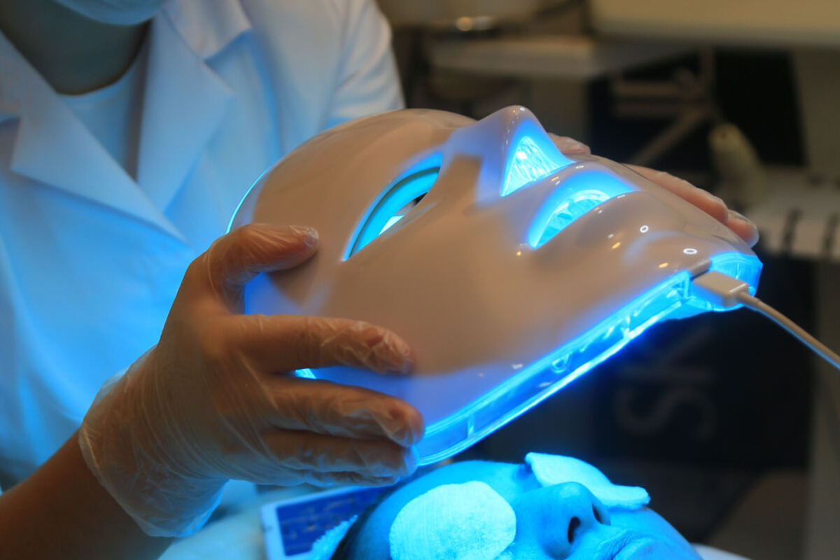 LED light therapy mask being positioned over a client during a facial treatment